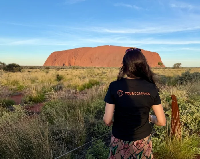Nainen katselee Ulurua aurinkoisena päivänä Uluru–Kata Tjutan kansallispuistossa Australiassa