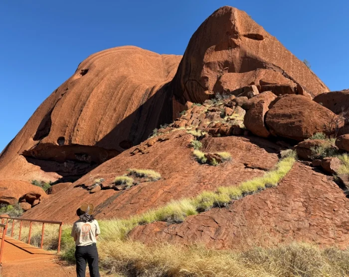 Uluru Australiassa, vaeltaja valtavan punaisen kalliomuodostelman juurella