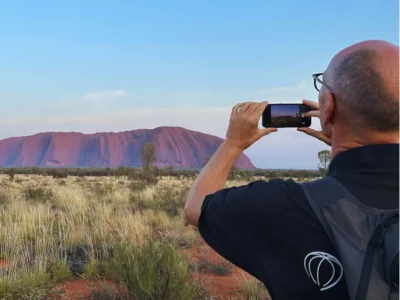 Mies ottaa kuvan Ulurusta Australiassa matkapuhelimella