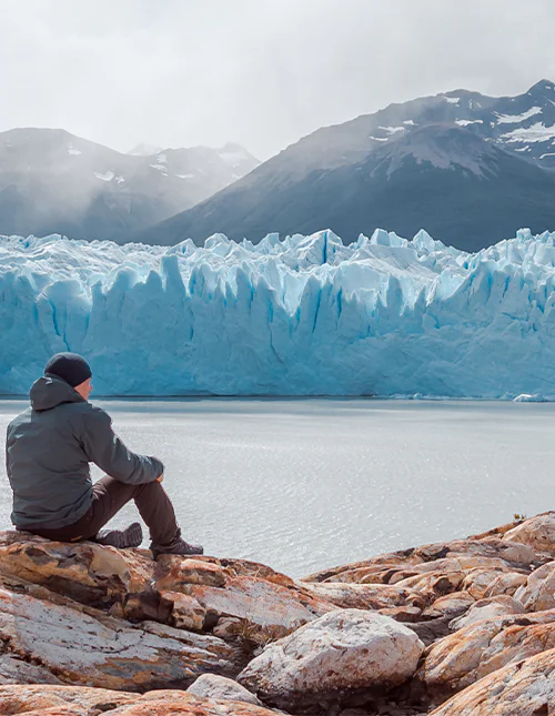 Mies istuu Perito Morenon jäätikön edustalla Los Glaciaresin kansallispuistossa