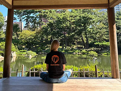 Nainen TourCompassin T-paidassa kauniissa japanilaisessa puutarhassa Hiroshimassa