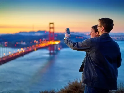 Mies ja nainen ottavat kuvan Golden Gate -sillasta auringonlaskun aikaan