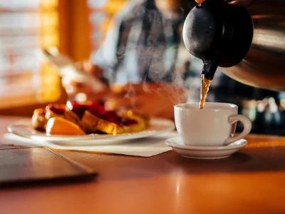 Mies istuu dinerissä syömässä vohveleita ja juomassa kahvia