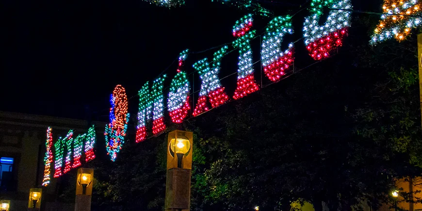 Pimeässä hohtava kyltti, jossa lukee ”Vive Mexico” Meksikon lipun väreissä