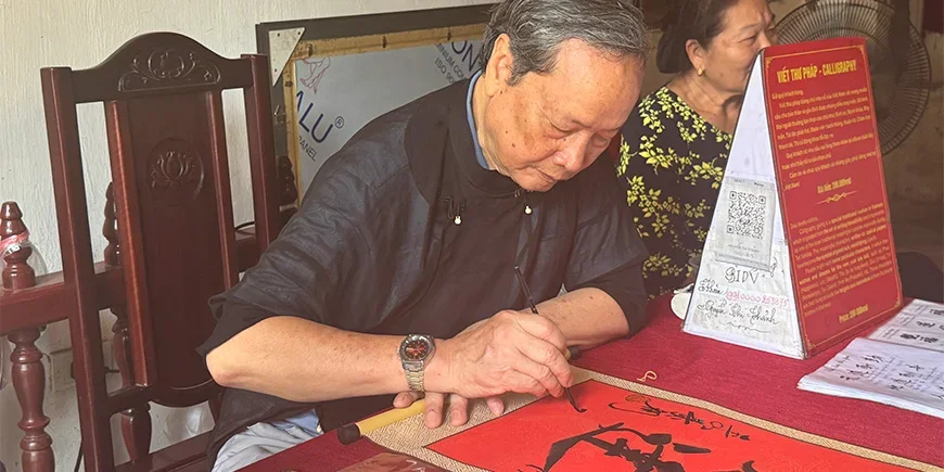 Vietnamilainen mies tekemässä kalligrafiaa