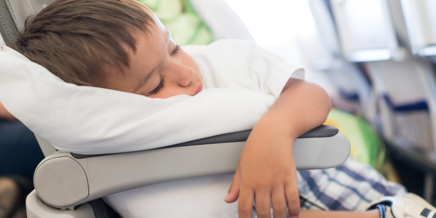 Poika nukkuu tyynyllä lentokoneessa
