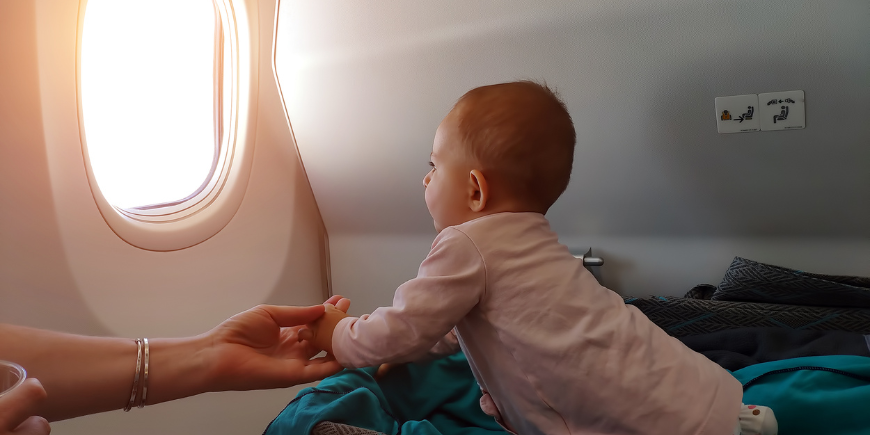 Pieni vauva katsoo ulos lentokoneen ikkunasta