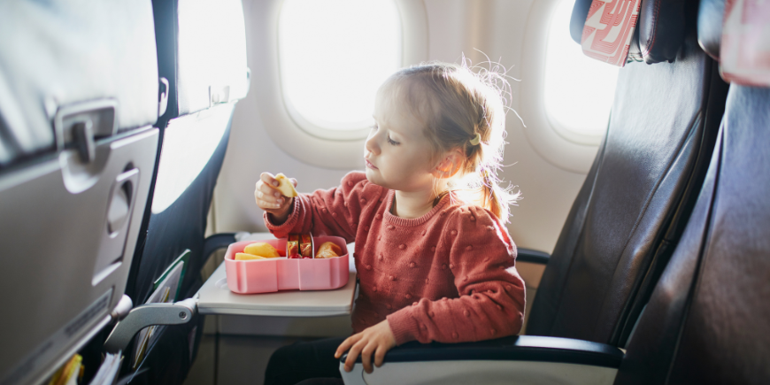 Lapsi syö välipalaa istuimella lentokoneessa