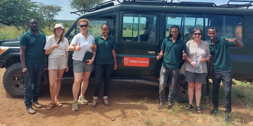 Safarimatkailijoita ja oppaita seisomassa safariauton vieressä Afrikassa