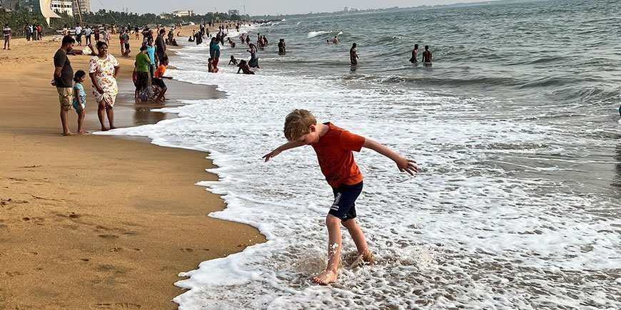 Poika kävelemässä vesirajassa hiekkarannalla Sri Lankassa