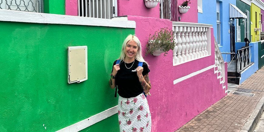 Catriona seisoo Bo-Kaapin värikkäiden talojen edessä Kapkaupungissa.