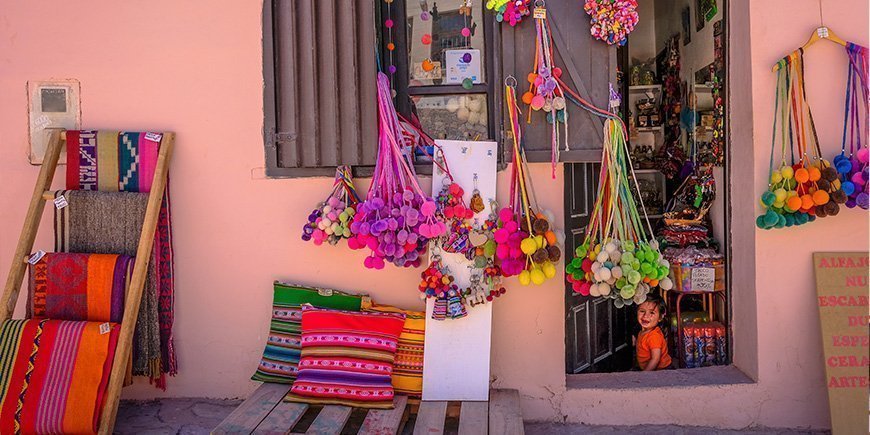 Pieni paikallinen kauppa Purmamarcassa, Argentiinassa ja ovella istuva tyttö.