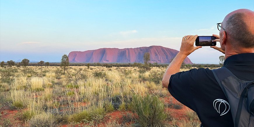 Mies ottaa kännykkäkuvan Ulurusta Australiassa