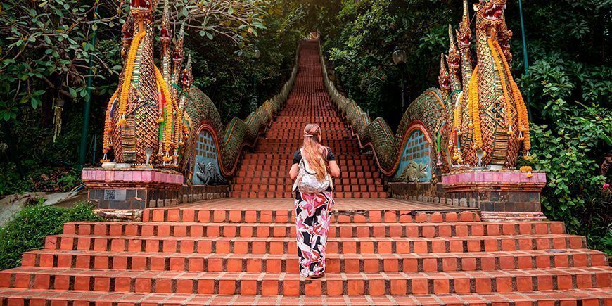 Nainen kiipeämässä portaita Doi Suthepin temppelissä Chiang Maissa, Thaimaassa.