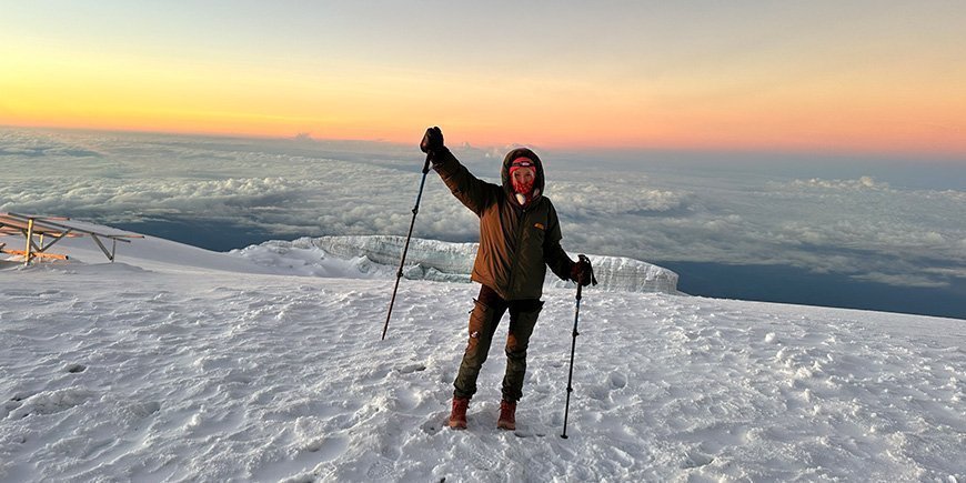 Nainen seisoo lumessa Kilimanjaron huipulla.