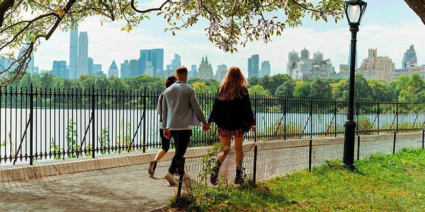 Pariskunta kävelee käsi kädessä aurinkoisella säällä Central Parkissa, New Yorkissa.