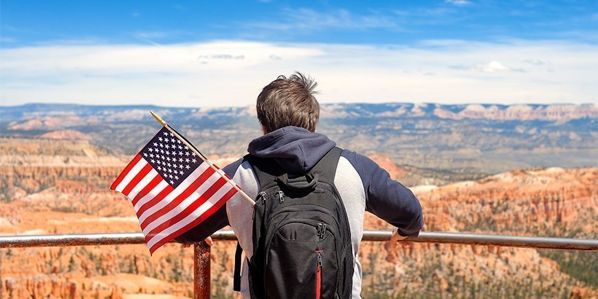 Mies kantaa repussaan Yhdysvaltain lippua ihaillessaan Bryce Canyonia Utahissa.