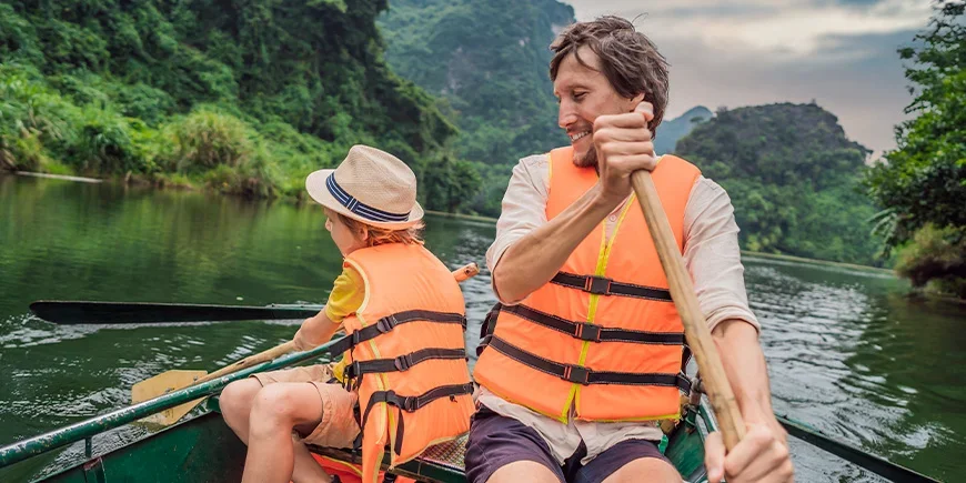 Isä ja poika veneilevät Ninh Binhissä, Vietnamissa