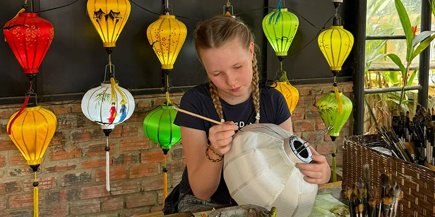 Tyttö maalaa lyhtyjä Hoi Anissa Vietnamissa