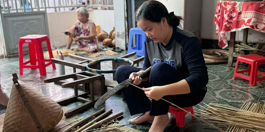 Vietnamilainen nainen valmistaa matkamuistoja kookoksesta